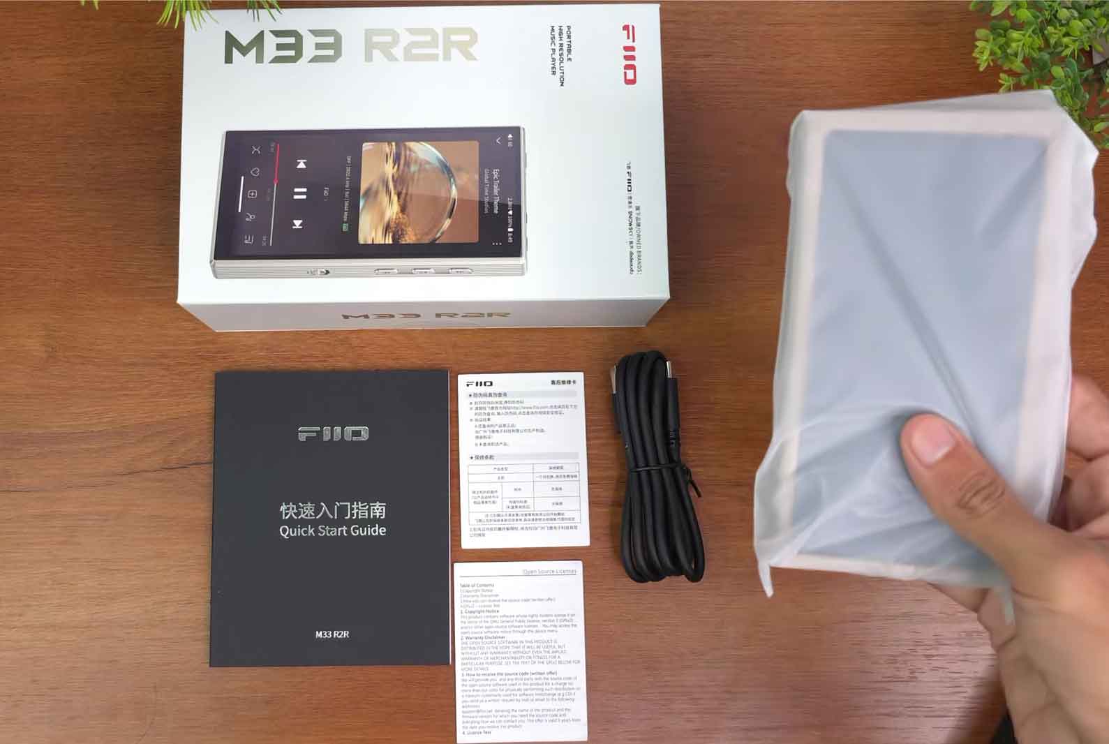 FiiO M33 R2R unboxing showing retail box, manual, charging cable, and portable digital audio player